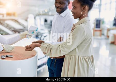 bella coppia carina si sono riuniti in showroom auto, sono controllati per covid-19, coronavirus, malattia con l'uso di dispositivo speciale Foto Stock