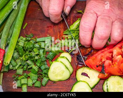 Affettare il prezzemolo verde con un coltello su un tagliere. Foto Stock