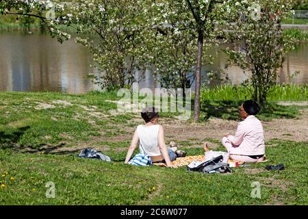 Umea, Norrland Svezia - 10 giugno 2020: Due donne di diverse nazionalità hanno un picnic Foto Stock