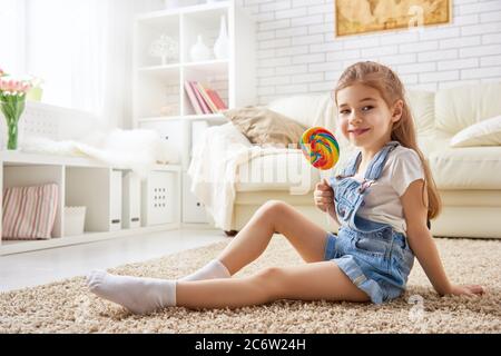 divertente bambina gioca a casa. ragazza mangiare caramelle e riposo. ricreazione e intrattenimento a casa. Foto Stock