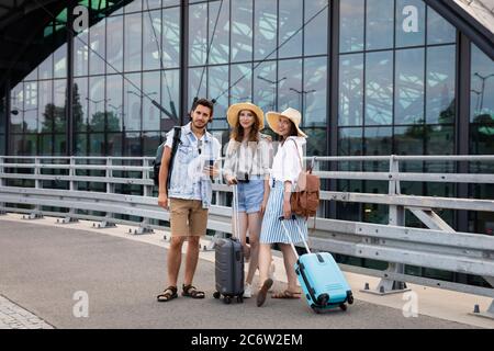 Una compagnia di giovani, felici turisti alla stazione ferroviaria. Gli amici si rallegrano per le vacanze e i viaggi. Foto Stock