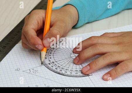 Mettere in primo piano le mani del bambino che misura l'angolo con il goniometro. Foto Stock