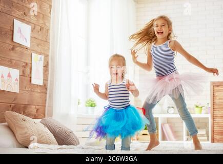 due ragazze carine bambini che giocano e si divertono nella stanza dei bambini. sorelle amorevoli che saltano sul letto. Foto Stock