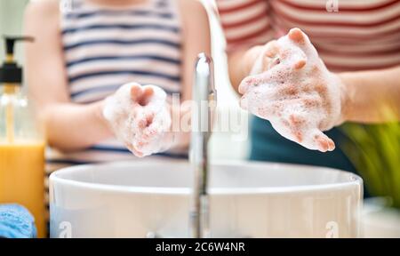 Bambini e adulti si lavano le mani. Protezione contro infezioni e virus. Primo piano. Foto Stock