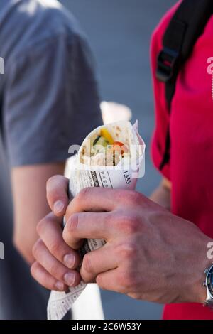 Un uomo che tiene un involucro ad un mercato di cibo di strada. Foto Stock
