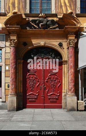 Doppia porta d'ingresso in legno rosso d'epoca ornata con sculture decorative, colonne, sculture e modanature. Piazza del mercato (Rynek). Wroclaw. Polonia. Foto Stock