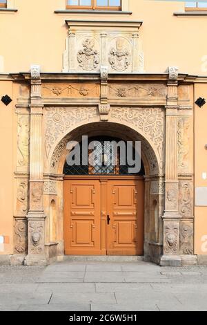 Porta d'ingresso doppia in legno d'epoca arancione decorata con sculture decorative, pilastri, sculture e modanature. Piazza del mercato (Rynek). Wroclaw. Polonia. Foto Stock