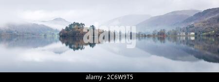 Riflessi specchio a Grasmere, English Lake District, in una mattinata perfettamente ancora d'autunno con il Daffodil Hotel e l'Isola prominente nella scena. Foto Stock