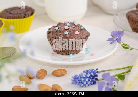 Muffin al biscotto al cioccolato e cosparsi di cuori su fondo bianco. Dessert festivo di San Valentino Foto Stock