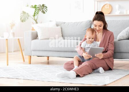 Sorridente Madre e il suo adorabile bambino che guardano i cartoni sul tablet digitale insieme Foto Stock