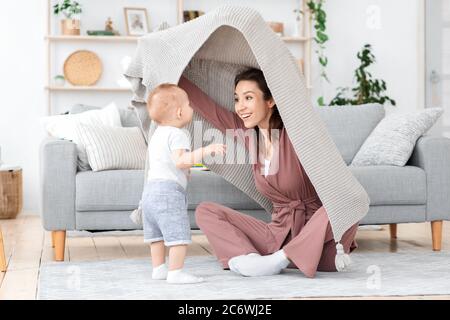 Mamma felice giocando con il figlio del toddler a casa, Pechino da sotto coperta Foto Stock