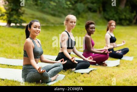 Belle Signore in abbigliamento sportivo impegnato in meditazione yoga in bellissimo parco verde, spazio copia Foto Stock