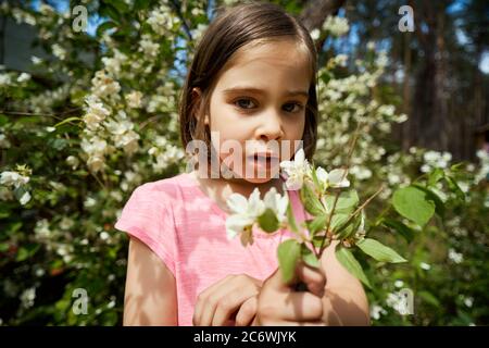 adorabile ragazza che fa i volti con fiore di gelsomino Foto Stock