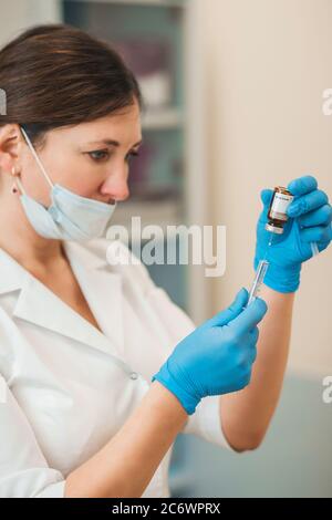 La dottoressa aspira una soluzione in una siringa da una fiala - vaccinazione - preparazione di un'iniezione Foto Stock