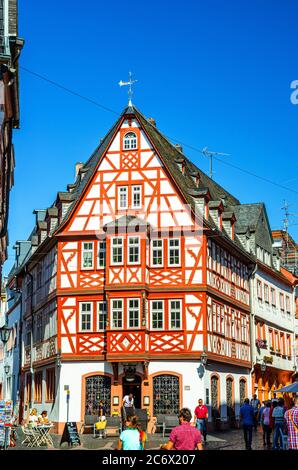 Magonza, Germania, 24 agosto 2019: Case tradizionali tedesche con facciata tipica in legno in stile fachwerk e turisti a piedi lungo la strada acciottolata nel centro storico medievale della città Foto Stock