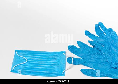 Maschera medica blu e un paio di guanti isolati su sfondo bianco. Spazio di copia Foto Stock