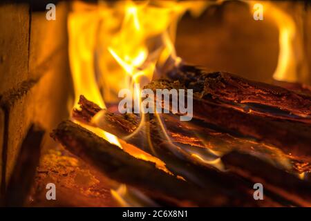 La fiamma incenerisce la legna da ardere e la trasforma in cenere, primo piano, profondità di campo poco profonda. Sfolgitiamo in una stufa grande. Natura struttura di fuoco. La fiamma di Foto Stock