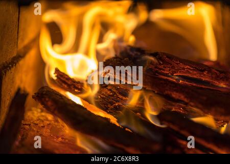 La fiamma incenerisce la legna da ardere e la trasforma in cenere, primo piano, profondità di campo poco profonda. Sfolgitiamo in una stufa grande. Natura struttura di fuoco. La fiamma di Foto Stock