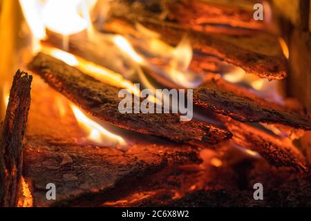 La fiamma incenerisce la legna da ardere e la trasforma in cenere, primo piano, profondità di campo poco profonda. Sfolgitiamo in una stufa grande. Natura struttura di fuoco. La fiamma di Foto Stock