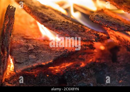 La fiamma incenerisce la legna da ardere e la trasforma in cenere, primo piano, profondità di campo poco profonda. Sfolgitiamo in una stufa grande. Natura struttura di fuoco. La fiamma di Foto Stock