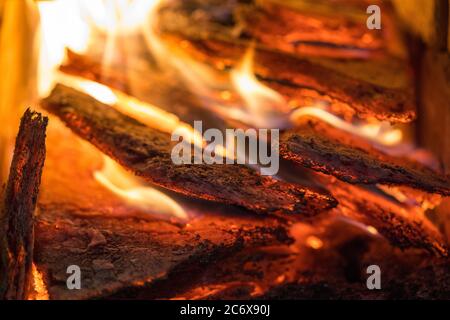 La fiamma incenerisce la legna da ardere e la trasforma in cenere, primo piano, profondità di campo poco profonda. Sfolgitiamo in una stufa grande. Natura struttura di fuoco. La fiamma di Foto Stock