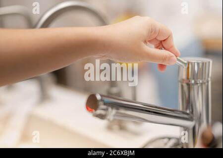Mano femminile scelta del rubinetto di cucina in acciaio inossidabile per l'uso all'interno della casa e il nuovo design per decorare in cucina. Foto Stock