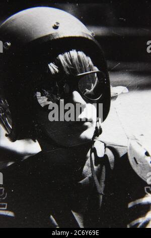 Fine anni '70 vintage nero e bianco stile di vita fotografia di un ragazzo che indossa un casco da corsa e l'aspetto buono. Foto Stock