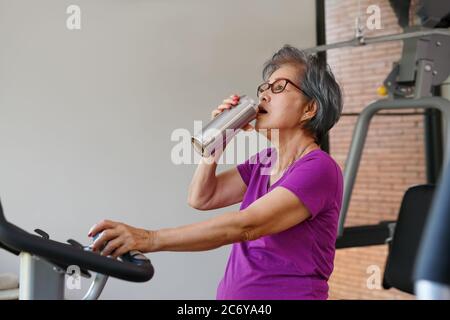donna anziana che fa esercizi in palestra Foto Stock