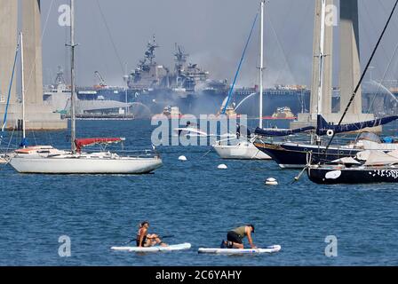 San Diego, California, Stati Uniti. 12 luglio 2020. In questa prospettiva da Coronado, CA, la nave della Marina statunitense USS Bonhomme Richard (LHD-6) brucia durante tutto il giorno dopo un incidente che coinvolgeva un tamburo da 55 galloni utilizzato per gli attrezzi di pulizia incendiati sulla nave d'assalto anfibia di 843 piedi Domenica mattina alla base navale di San Diego. Credit: John Gastaldo/ZUMA Wire/Alamy Live News Foto Stock