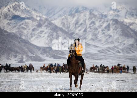 Una turista straniera cavalcava un cavallo locale durante una partita di Kok Boru nel Chuy Oblast del Kirghizistan vicino alla capitale Bishkek. Foto Stock