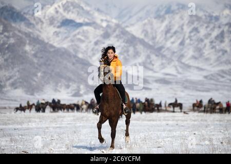 Una turista straniera cavalcava un cavallo locale durante una partita di Kok Boru nel Chuy Oblast del Kirghizistan vicino alla capitale Bishkek. Foto Stock