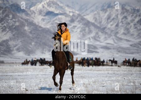 Una turista straniera cavalcava un cavallo locale durante una partita di Kok Boru nel Chuy Oblast del Kirghizistan vicino alla capitale Bishkek. Foto Stock