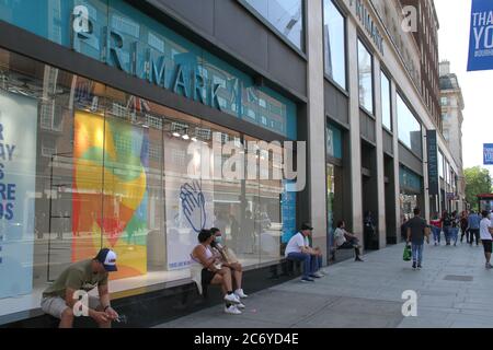 Londra, Regno Unito. 12 luglio 2020. La gente si siede fuori dal negozio Primark su Oxford Street durante la riapertura. I londinesi hanno cominciato lentamente a tornare alla 'normale' con i negozi riaperti su Oxford Street. Questa settimana il governo ha consigliato l'apertura di palestre e piscine dal 11 luglio. Credit: SOPA Images Limited/Alamy Live News Foto Stock