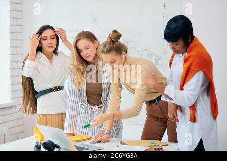 Donne diverse di successo si sono riunite per discutere di nuovo progetto di business, idee e condividere esperienze tra loro. Giovani Signore che indossano abiti casual wor Foto Stock