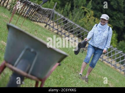 Vienna, Austria. 12 luglio 2020. Una donna partecipa al Bauerngolf in una fattoria a Vienna, Austria, 12 luglio 2020. "Bauerngolf" significa che il golf degli agricoltori è un divertente evento sportivo fondato dagli agricoltori locali a Vienna, che si tiene in alcuni fine settimana da giugno a ottobre. Questa attività sportiva utilizza scarpe in gomma come oggetto di lancio e vari tipi di attrezzi agricoli come obiettivi per segnare più giri di lancio. Il concorso si svolge dal 2008, e chiunque sia interessato può partecipare gratuitamente. Credit: Guo Chen/Xinhua/Alamy Live News Foto Stock