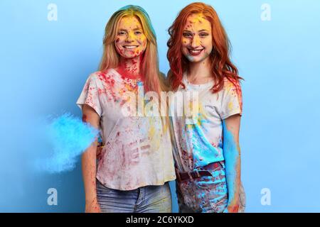 due amici felici che abbracciano e si levano in piedi su sfondo blu. studio shot, celebrazione del frolic. bellezza, concetto d'arte Foto Stock