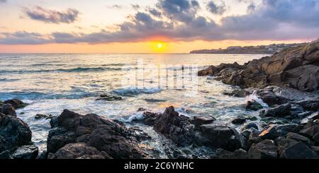 costa dell'oceano al tramonto. splendido paesaggio con rocce in acqua. splendido paesaggio nuvoloso sopra il sole e l'orizzonte. concetto di calma e medi Foto Stock