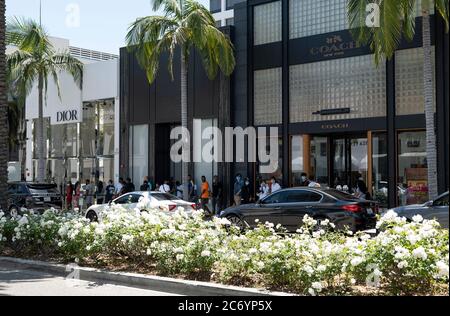 Beverly Hills, CA/USA - 12 luglio 2020: Linea di clienti socialmente distanzianti in maschere facciali aspettano fuori negozi di lusso su Rodeo Drive Foto Stock