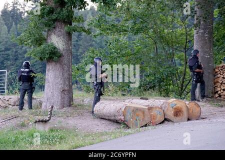 Oppenau, Germania. 13 luglio 2020. Gli agenti di polizia si trovano fuori da una zona boscosa su una strada vicino a Oppenau. Il giorno prima, un uomo aveva minacciato e disarmato gli ufficiali di polizia durante un'ispezione. Poi fuggì. Un grande contingente sta cercando il fuggitivo. Credit: Sven Kohls/SDMG/dpa/Alamy Live News Foto Stock