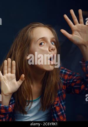 La bambina fa il viso appoggiarsi al vetro Foto Stock