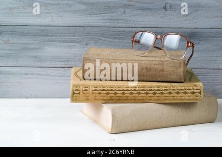 Pila di libri vecchi e vetri di lettura su sfondo di legno Foto Stock