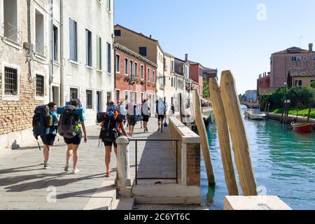 Venezia, 2018 aprile. Un gruppo di ragazzi-scout cammina attraverso i canali della città lentamente portando il loro zaino in una rara escursione Foto Stock