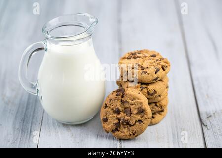 Caraffa in vetro con biscotti al latte e al cioccolato su sfondo di legno Foto Stock