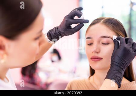 Sopracciglia artista viso pulito con spugna professionale di giovane donna Foto Stock