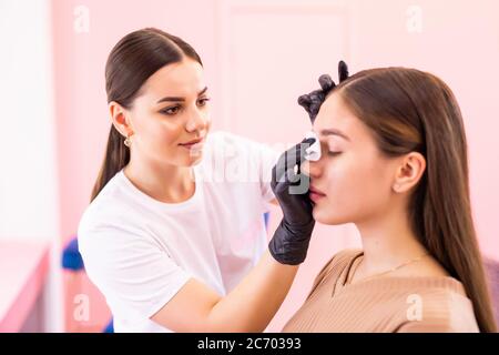 Sopracciglia artista viso pulito con spugna professionale di giovane donna Foto Stock