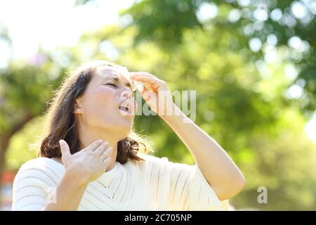 Donna adulta che sudore con calore stroke pulizia con tessuto nel parco Foto Stock