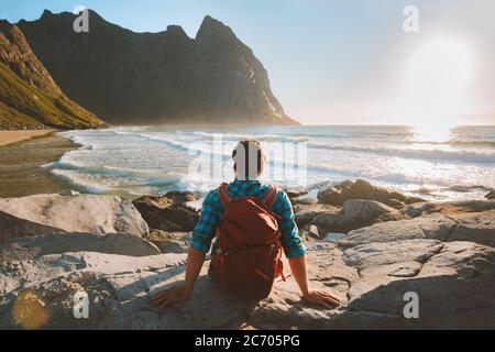 Uomo seduto sulla spiaggia di Kvalvika godendo vista oceano viaggio vacanze eco turismo outdoor backpacking in Norvegia sano stile di vita viaggio estivo Foto Stock