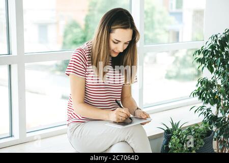 L'artista digitale ragazza disegna con uno stilo sul tablet. È una studentessa e sta studiando disegno o è questa la sua professione professionale. Foto Stock