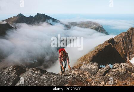 Escursionista uomo arrampicata sulla montagna sopra le nuvole viaggio escursionismo con zaino all'aperto avventura estrema vacanza attiva sano stile di vita trekking in No Foto Stock