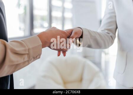 vista tagliata di donne d'affari scuotendo mano sin ufficio Foto Stock